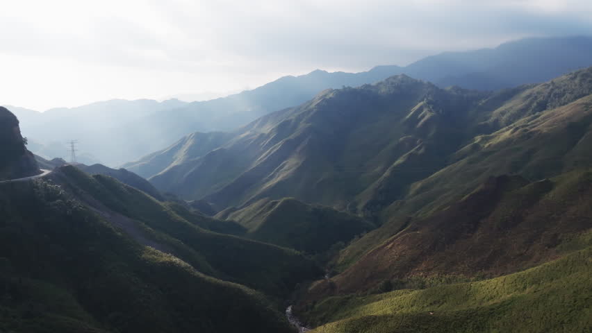 Gliding aerial footage presents a wide scenic ridge of rice terraces with layered mountains beyond at sunrise in Mui Giay, Mu Cang Chai district, Yen Bai province, Vietnam.