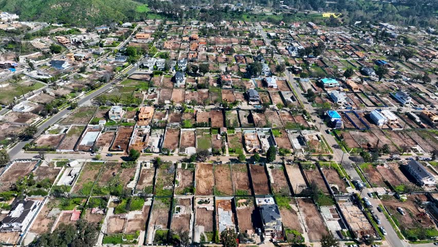 Residential neighborhood in the Palisades recovering from a recent wildfire highlighting damaged areas and ongoing reconstruction, aerial footage
