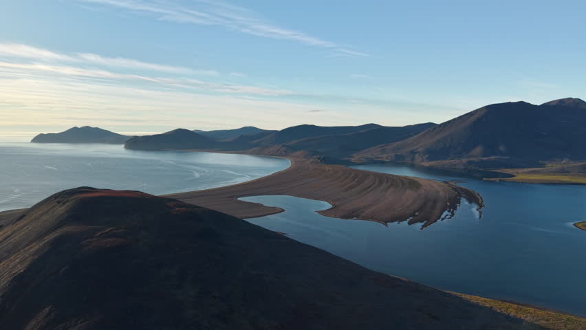 Aerial shot shows pan revealing a sandy cape between lagoon and ocean at Rumilet Bay in Chukotka. Autumn evening light stays soft and clear. Scenic arctic wilderness for travel tourism and exploration