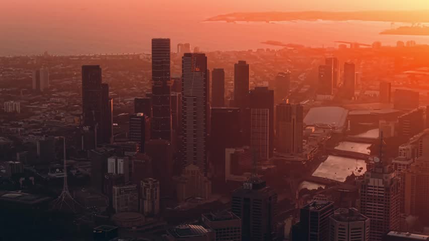 Golden sunset light over Melbourne city towers, aerial pullback centered on central business district