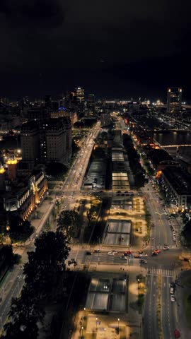 Vertical aerial zoom in of Paseo del Bajo corridor and surrounding city blocks at night in Buenos Aires. Bright traffic lines and modern skyline.