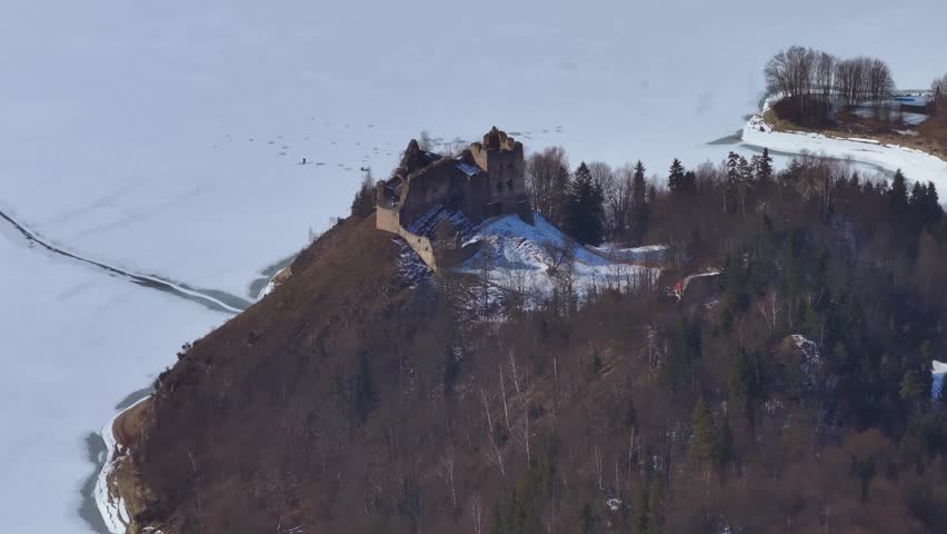 Aerial view of historic castle on a snowy hilltop in winter landscape