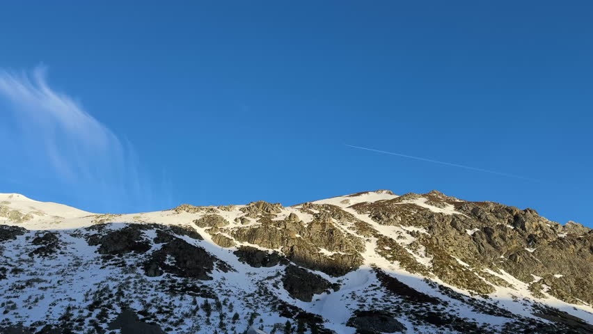 Airplane contrail flying over snowy mountains