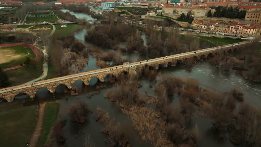 Aerial view of the ancient Roman stone bridge in Salamanca crossing the Tormes River. Historic landmark and architectural heritage in Castilla y León, Spain