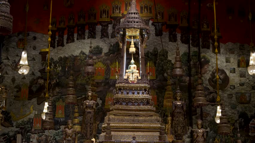 Emerald Buddha sits on a gilded altar inside Wat Phra Kaew or Temple of the Emerald Buddha, Bangkok, handheld static shot.