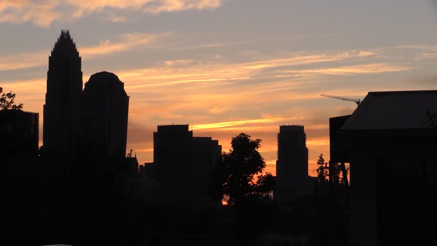 Captivating sunset over a cityscape with silhouetted skyscrapers. The sky is painted with vibrant oranges and yellows, creating a stunning urban panorama. Calm, atmospheric, urban scene.