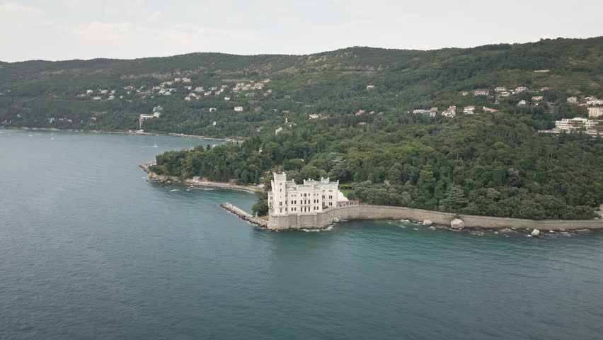 Elevate your story with a smooth 4K UHD drone orbit around Miramare Castle on the Gulf of Trieste, Italy, revealing cliffside walls and teal sea for promos.
