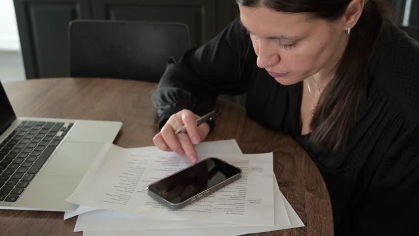 Middle-aged woman texting on smartphone in home living room. Everyday digital communication in domestic interior setting.