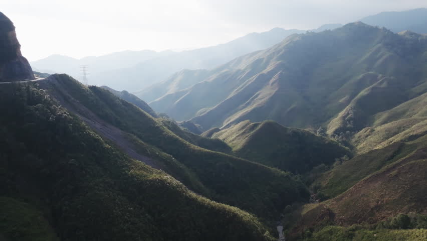Gliding aerial footage presents a wide scenic ridge of rice terraces with layered mountains beyond at sunrise in Mui Giay, Mu Cang Chai district, Yen Bai province, Vietnam.