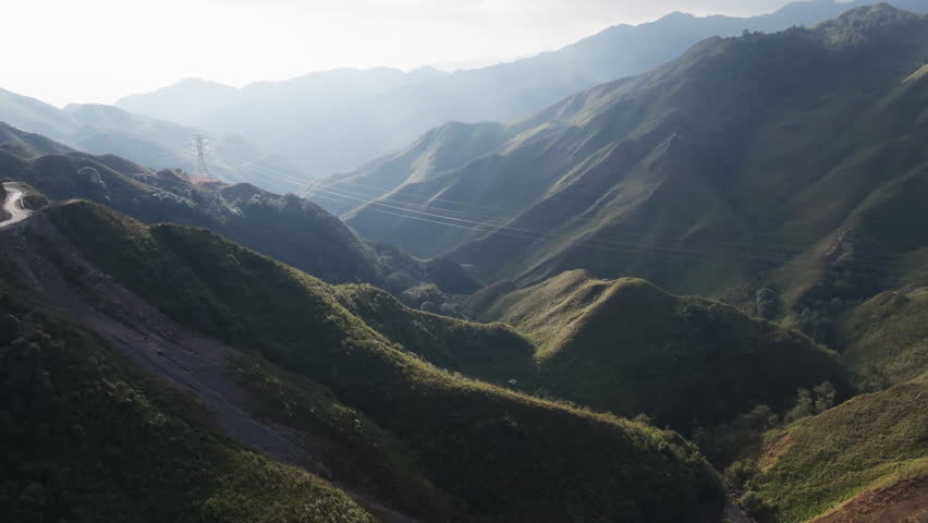 Gliding aerial footage presents a wide scenic ridge of rice terraces with layered mountains beyond at sunrise in Mui Giay, Mu Cang Chai district, Yen Bai province, Vietnam.