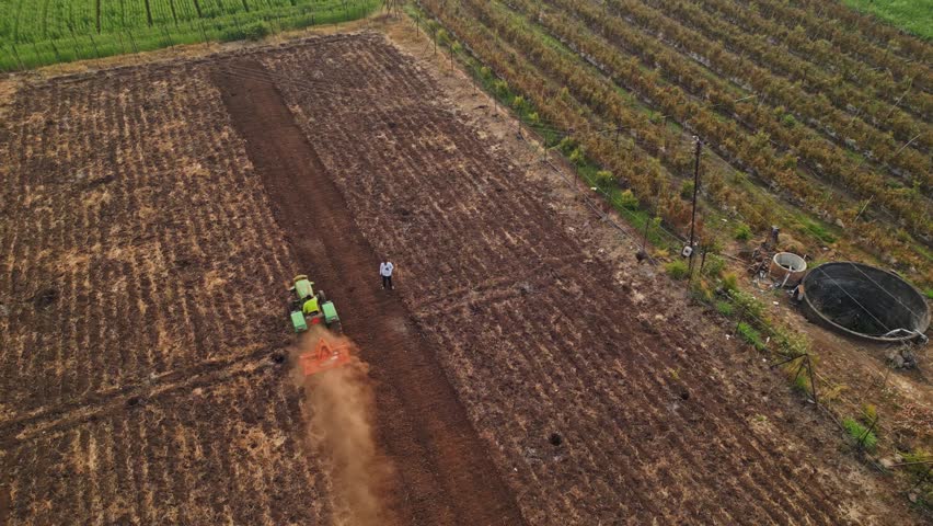 A drone captures Adgaon, Nashik farmland during harvest golden crops stretch across neat fields tractors and farmers at work highlighting rural life fertile soil and the natural beauty of Maharashtra