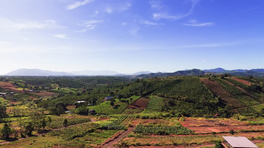 Explore the landscape of Lam Dong, Vietnam, where green fields meet hills under bright skies. This area shows the natural beauty of rural life and farming practices.