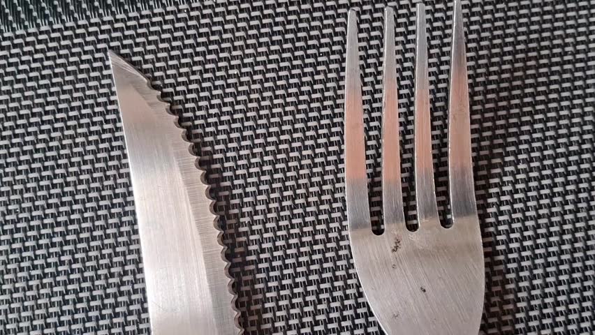 Stainless steel knife and fork on woven placemat