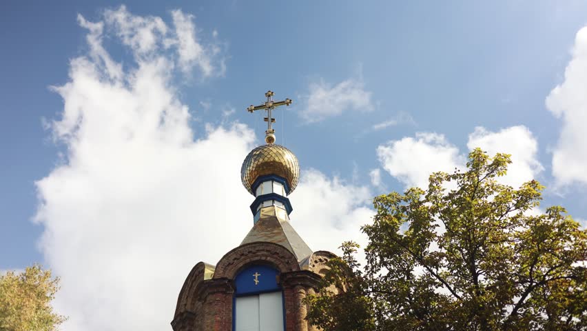 Orthodox church against the blue sky. Golden dome of the church with a cross. The sky floating clouds. St. Michael