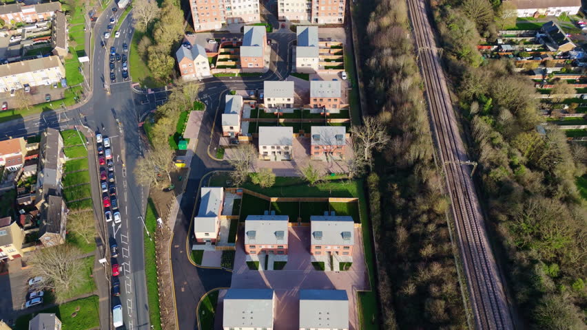 Reverse aerial view of new houses in Basildon, England, next to a road and railroad tracks