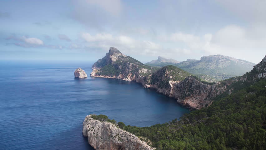 4K aerial footage of Beautiful Mallorca rocky coast covered with green forest. Balearic Sea as a part of Mediterranean Sea washing Es Colomer cape aerial view. Mallorca island, Balearic Islands, Spain