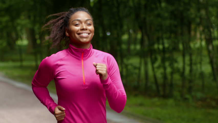Smiling African American Woman Jogging in a Park on a Sunny Day