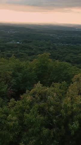 Vertical screen Sunset Over Farmland. Golden Twilight Over Rolling Landscape. Calm Dusk Illuminates Hills And Distant Fields. Peaceful Evening Scene With Soft Clouds And Sprawling