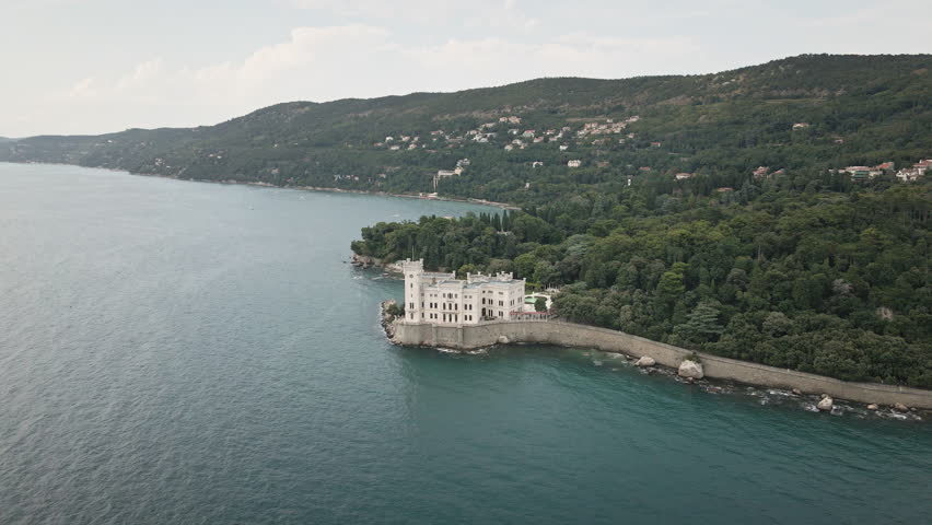Elevate your story with a smooth 4K UHD drone orbit around Miramare Castle on the Gulf of Trieste, Italy, revealing cliffside walls and teal sea for promos.
