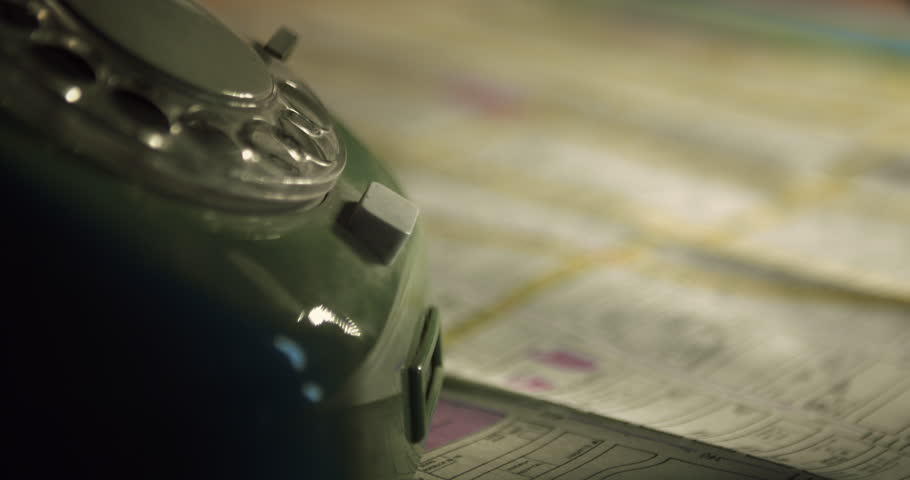 Hand holding a retro telephone receiver while gesturing toward a street map in the background. Ideal for vintage, noir, cold case, detective investigation