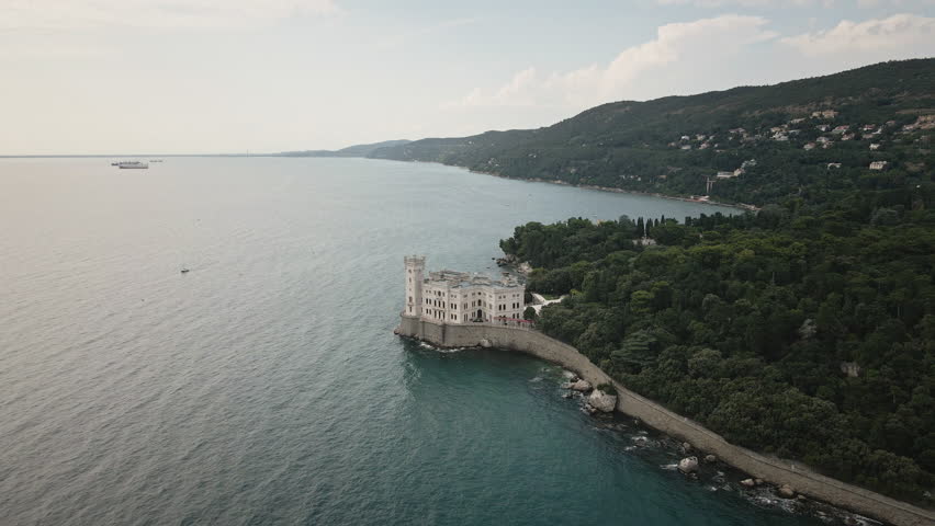 Elevate your story with a smooth 4K UHD drone orbit around Miramare Castle on the Gulf of Trieste, Italy, revealing cliffside walls and teal sea for promos.