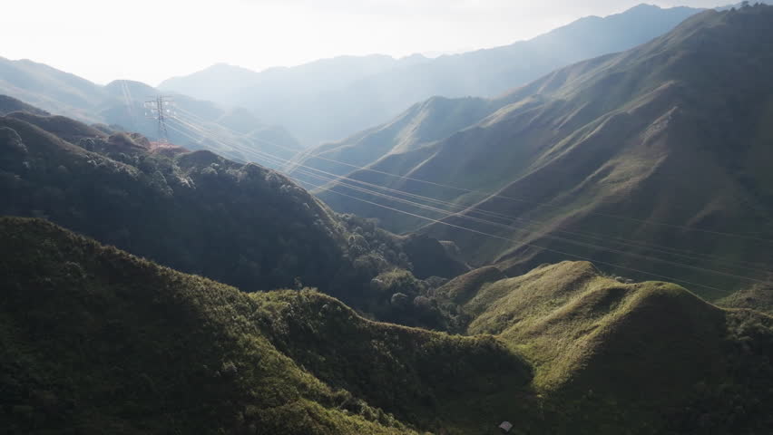 Gliding aerial footage presents a wide scenic ridge of rice terraces with layered mountains beyond at sunrise in Mui Giay, Mu Cang Chai district, Yen Bai province, Vietnam.