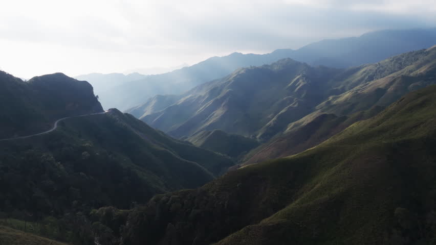 Gliding aerial footage presents a wide scenic ridge of rice terraces with layered mountains beyond at sunrise in Mui Giay, Mu Cang Chai district, Yen Bai province, Vietnam.