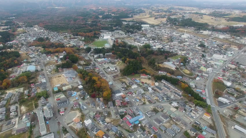 Aerial view of Fukushima residential area in Japan. Autumn foliage, houses, and distant wind turbines.