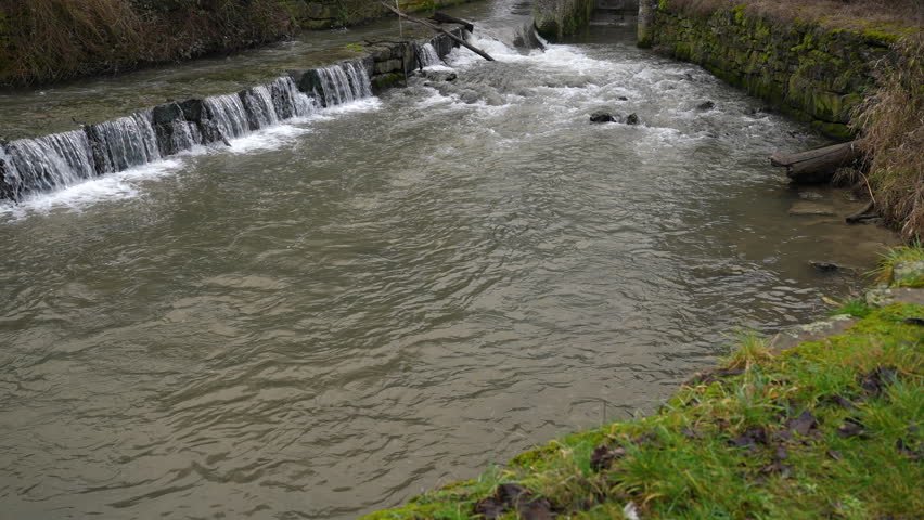 Small water step near old watermill in Belgium, tilt up view