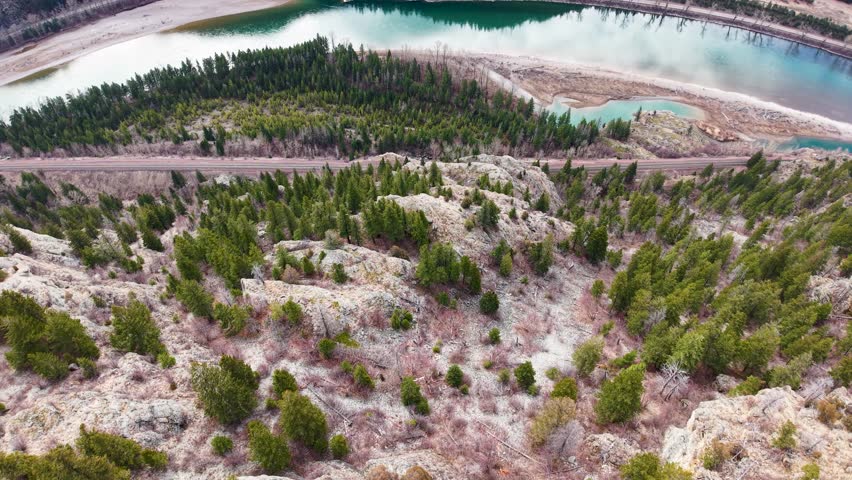 High-angle aerial shot of the turquoise Flathead River sweeping past an evergreen shoreline and small peninsula in the wilderness near Whitefish Montana
