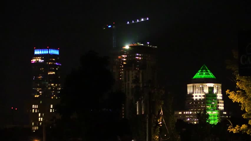 Captivating nighttime skyline of Charlotte, North Carolina, featuring the iconic green-lit crown of One Wells Fargo Center. The urban landscape glows under the serene night sky.