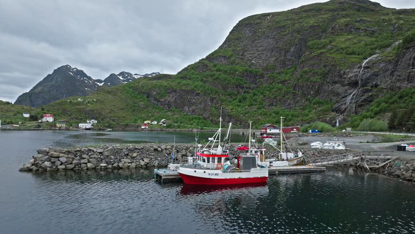 Drone view of boats and coastline in Lofoten Islands, Norway. Norwegian fishing harbor surrounded by dramatic Arctic mountains and sea.