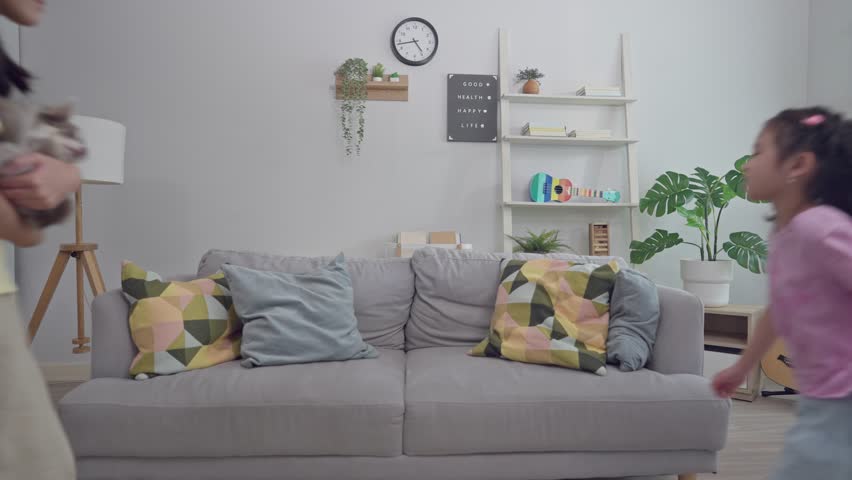 Portrait of Asian family sitting together on sofa in living room at home. Smiling parents, grandparents, and children enjoy quality time with a Chihuahua puppy, sharing a warm and loving family moment