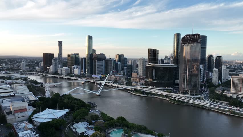 Steady drone shot at golden hour over the Brisbane River, holding Queens Wharf and The Star Brisbane towers with Neville Bonner Bridge and the CBD skyline, Brisbane, QLD, Australia