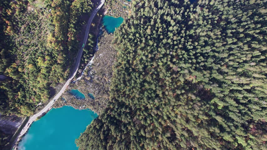 Drone view of Jiuzhaigou National Park in autumn in Sichuan Province China. It features cascading waterfalls, turquoise blue lakes, and stunning mountain valleys. 4K real time footage travel concept