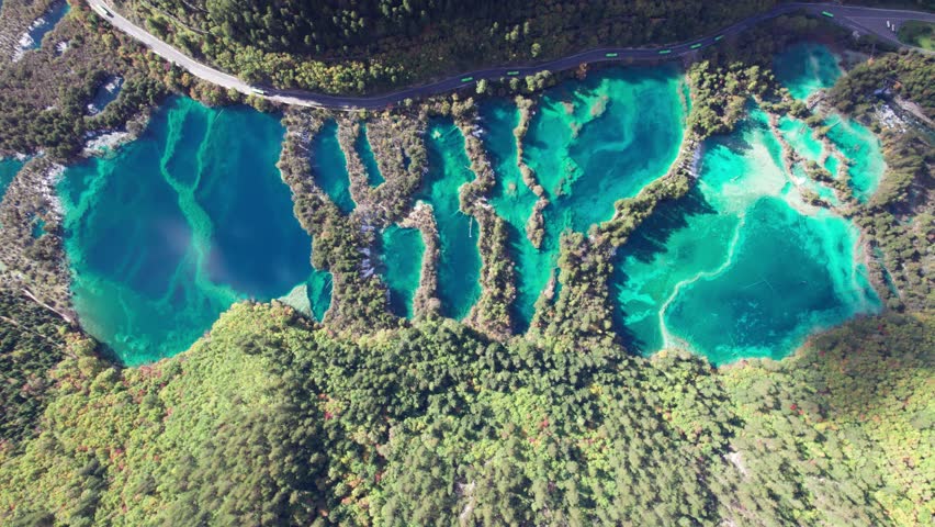 Drone view of Jiuzhaigou National Park in autumn in Sichuan Province China. It features cascading waterfalls, turquoise blue lakes, and stunning mountain valleys. 4K real time footage travel concept