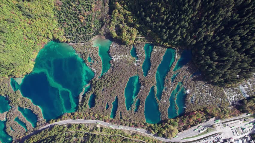 Drone view of Jiuzhaigou National Park in autumn in Sichuan Province China. It features cascading waterfalls, turquoise blue lakes, and stunning mountain valleys. 4K real time footage travel concept