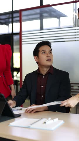 Businessman arguing during a meeting in an office. Colleagues are discussing a project, but they are having a disagreement and the man is stressed, covering his face with his hands.