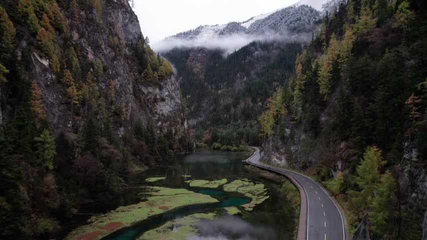 Drone view of Jiuzhaigou National Park in autumn in Sichuan Province China. It features cascading waterfalls, turquoise blue lakes, and stunning mountain valleys. 4K real time footage travel concept