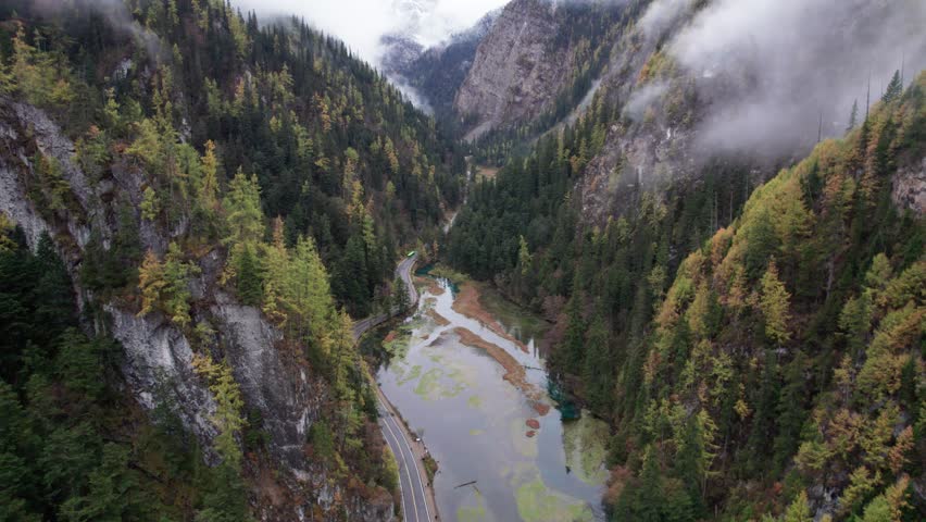 Drone view of Jiuzhaigou National Park in autumn in Sichuan Province China. It features cascading waterfalls, turquoise blue lakes, and stunning mountain valleys. 4K real time footage travel concept