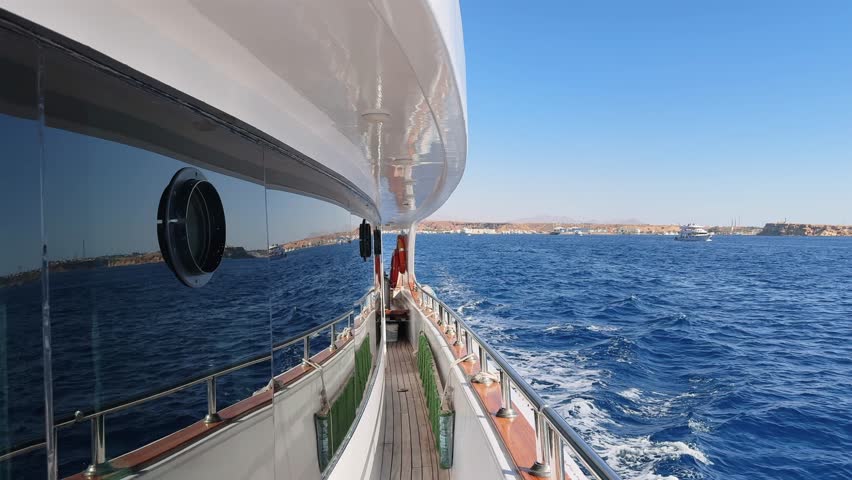 Luxury yacht side deck view with tinted window leaving sea port