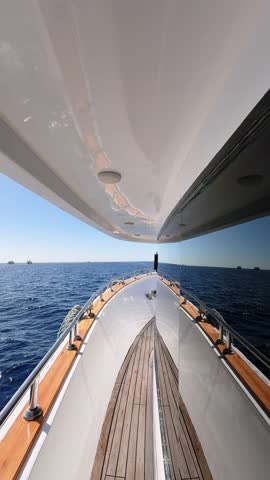 Vertical close up view of yacht deck side with tinted window floating in the blue sea water