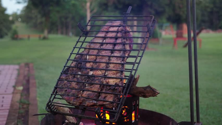 Close up of Argentinian barbecue scene with large ribs cuts cooking on grill, culinary latin culture