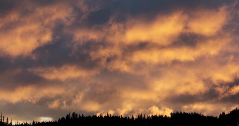 The sky is filled with clouds and the sun is setting. The clouds are orange and pink, creating a warm and peaceful atmosphere near mccall idaho