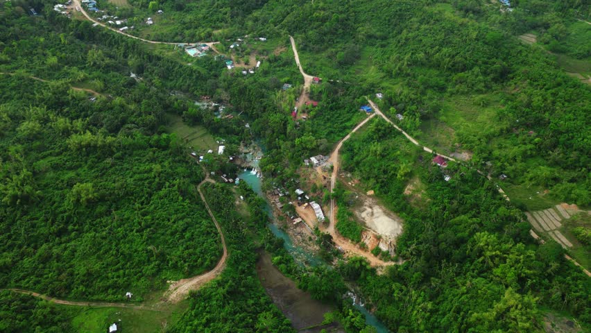 Wide high rotating view establishing shot reveals full view of road, walerfalls, Bolinao river flow and near by houses at Bolinao Falls 3 Bolinao Pangasinan Philippines.