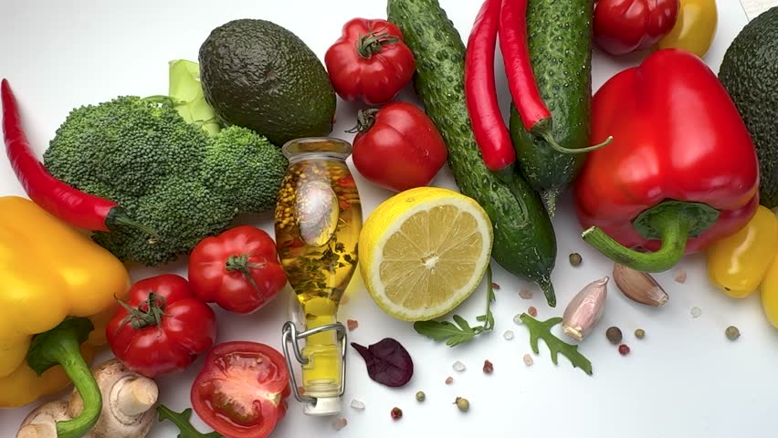 Colorful raw vegetables, spices, and olive oil composition on a white background for healthy eating