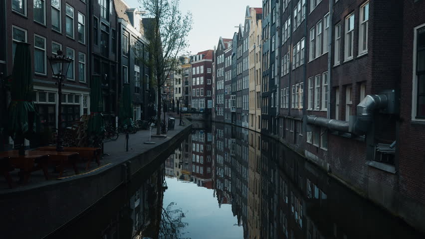 Curving Amsterdam canal, with the facades of historic Dutch houses reflected in the calm water Korte Niezel street