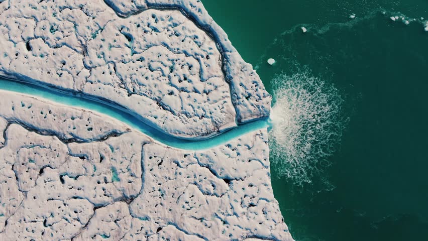 Top down drone view of meltwater waterfall on Nordauslandet glacier into Arctic sea
