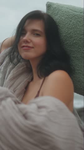 Intimate close-up of a woman wrapped in a warm blanket, posing calmly as focus drifts into softness.