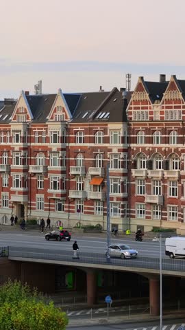 Urban street scene with historic red brick apartment buildings and traffic on a bridge